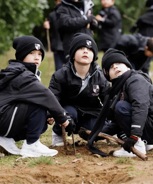 Pupils playing in a mud pit at Forest School