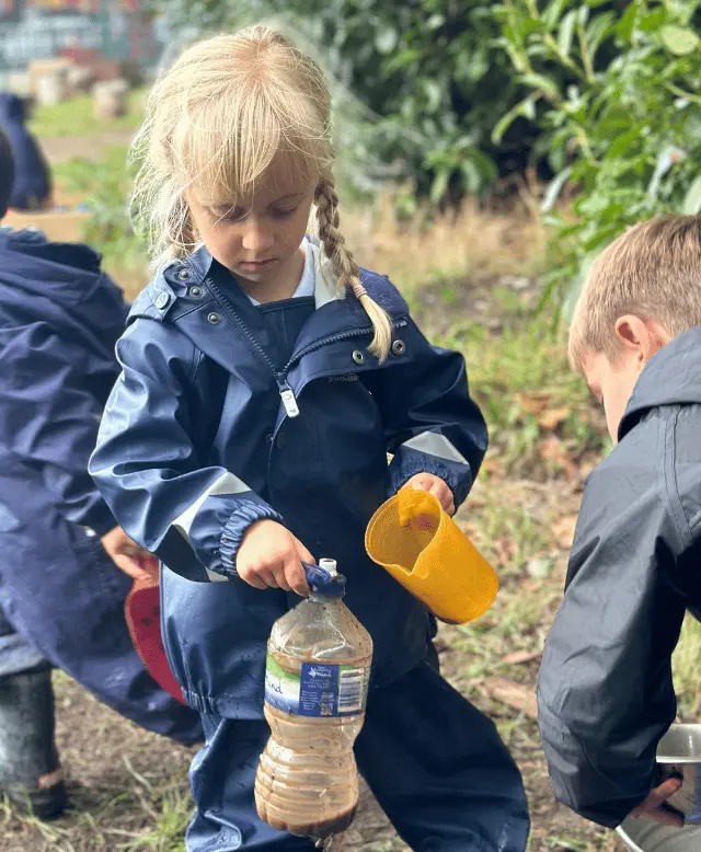 Girl playing with mud and water at forest school