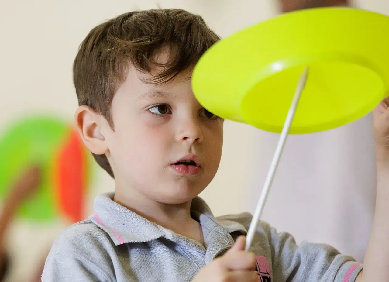 Boy trying to spin a yellow circus plate